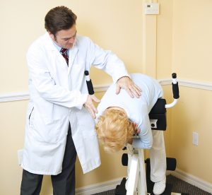 Chiropractor assists an elderly patient recovering from back pain